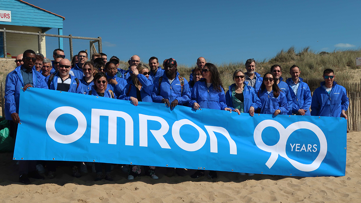 OMRON employees holding large banner which reads 'OMRON 90 Years'.